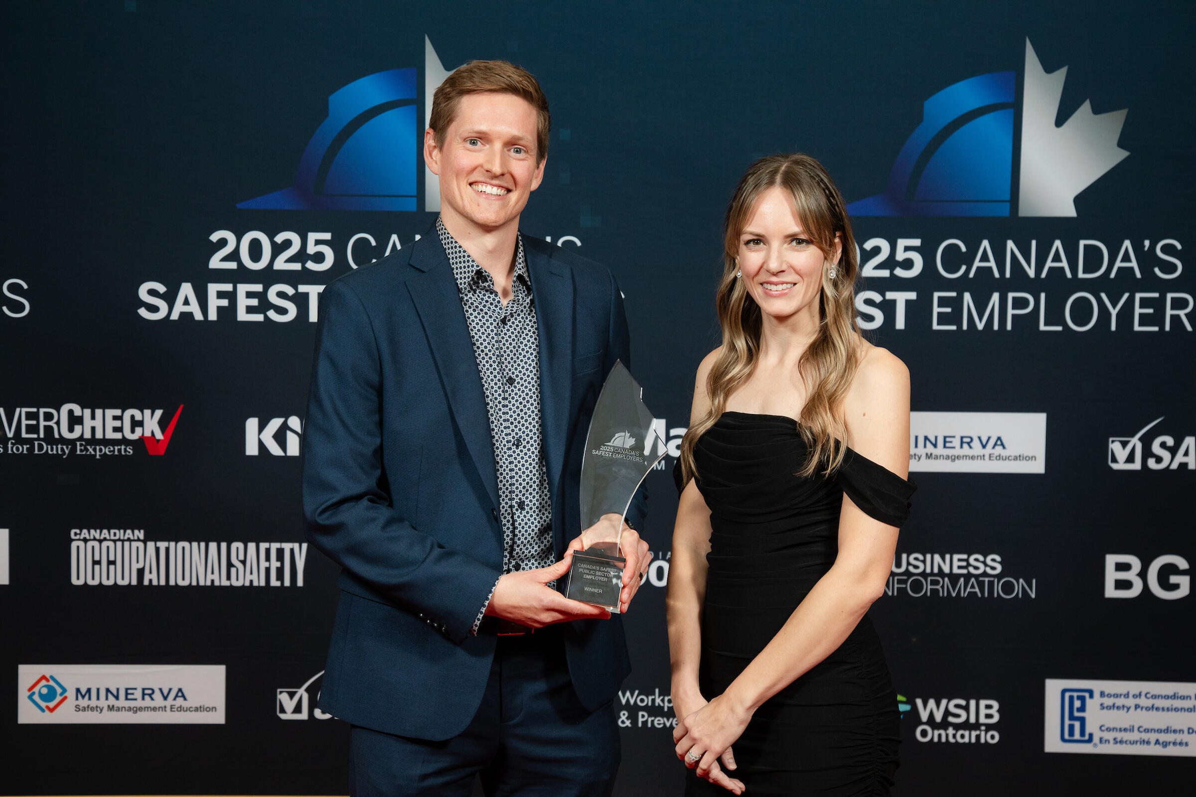 Man and woman holding award, smiling at camera