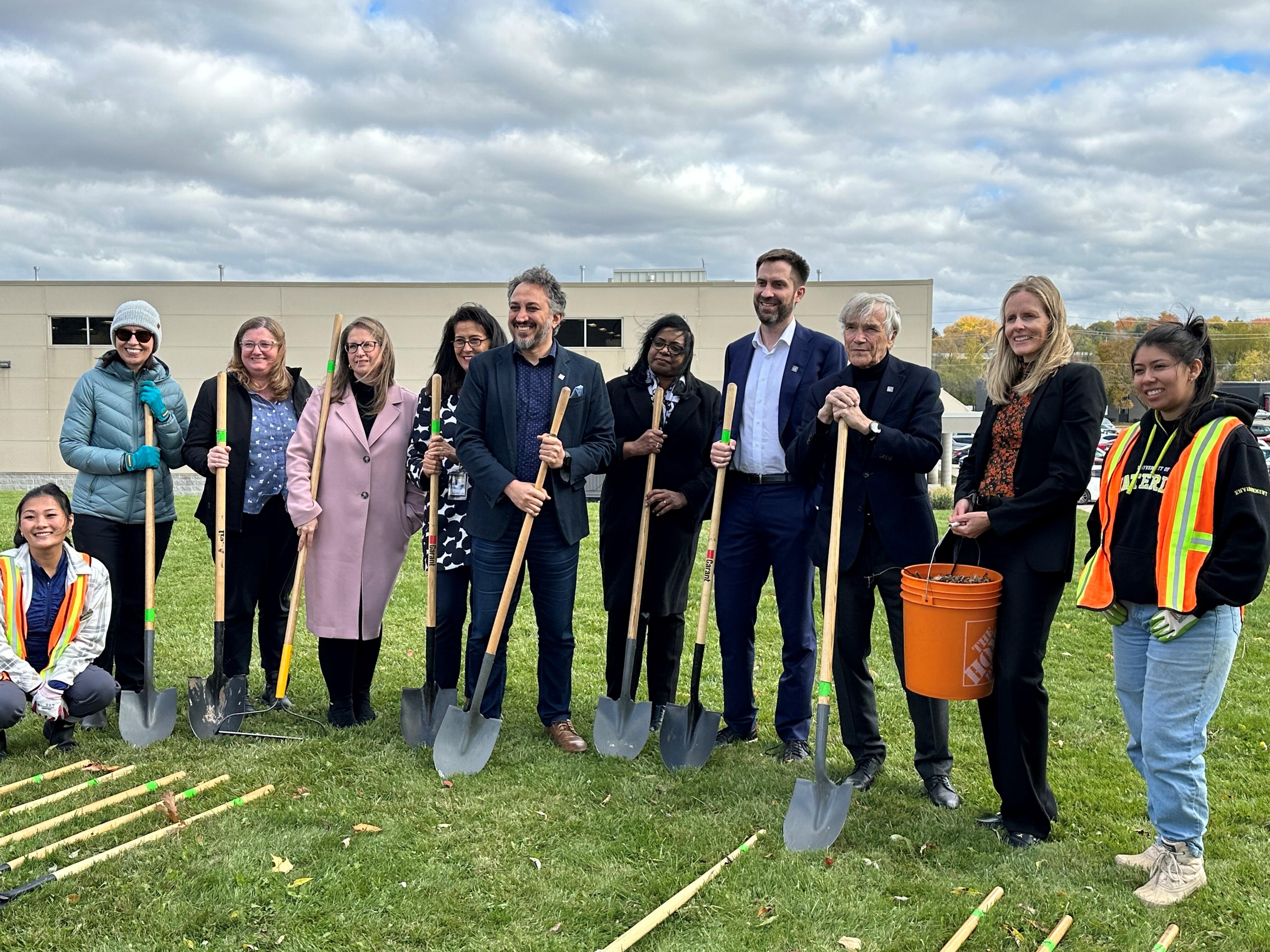 A group gathered with shovels posing for a photo